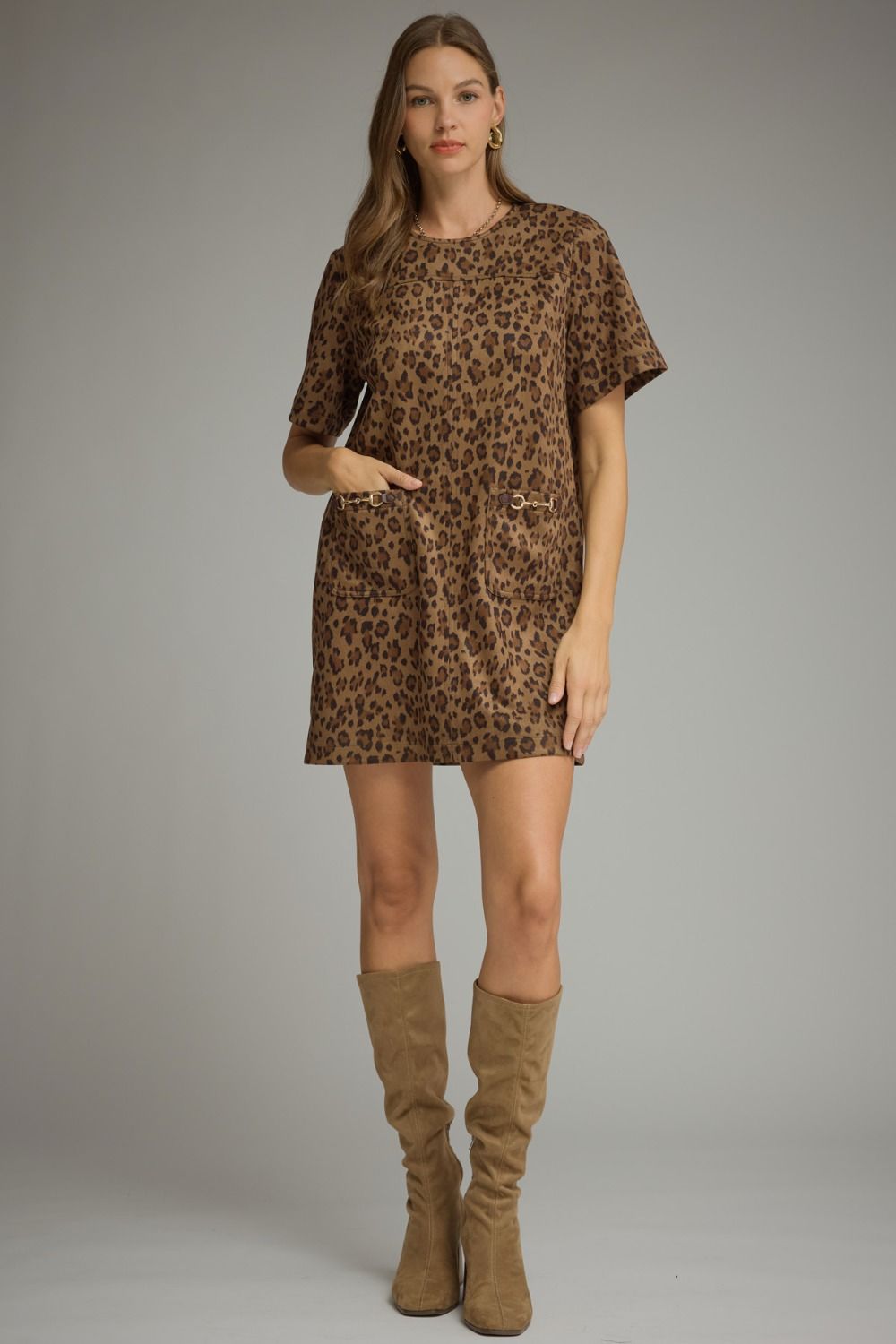 Leopard print short sleeve mini dress with a round neckline and back zipper. Front patch pockets with gold-tone horsebit detail.